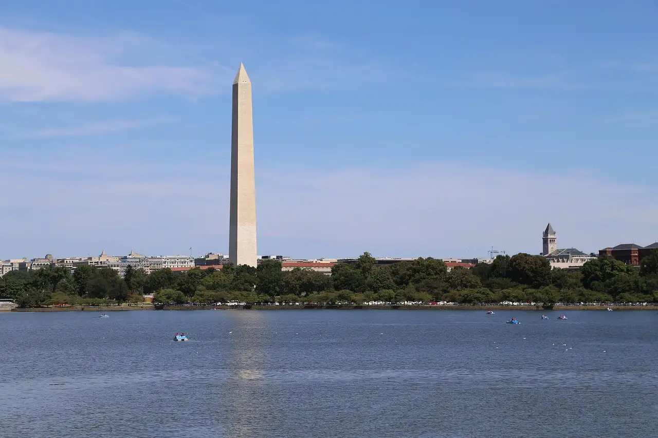 The Washington Monument rising above the tree line across a wide stretch of water.