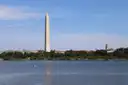 The Washington Monument rising above the tree line across a wide stretch of water.