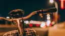 A bicycle handlebar in front of blurred city lights at night