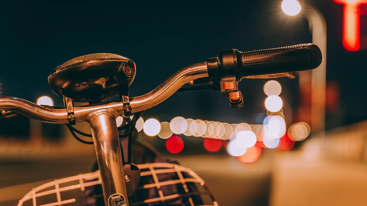 A bicycle handlebar in front of blurred city lights at night
