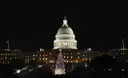 The U.S. Capitol at night with a lit Christmas tree on the lawn in front