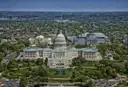 An aerial view of the US Capitol and the green grounds around it, with the city behind