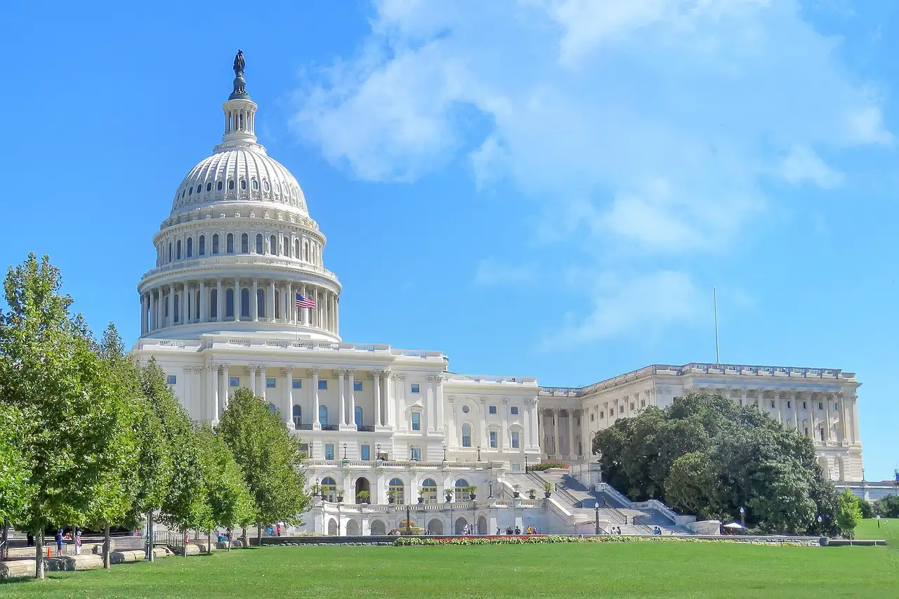 The US Capitol dome and west front above a green lawn in Washington, DC