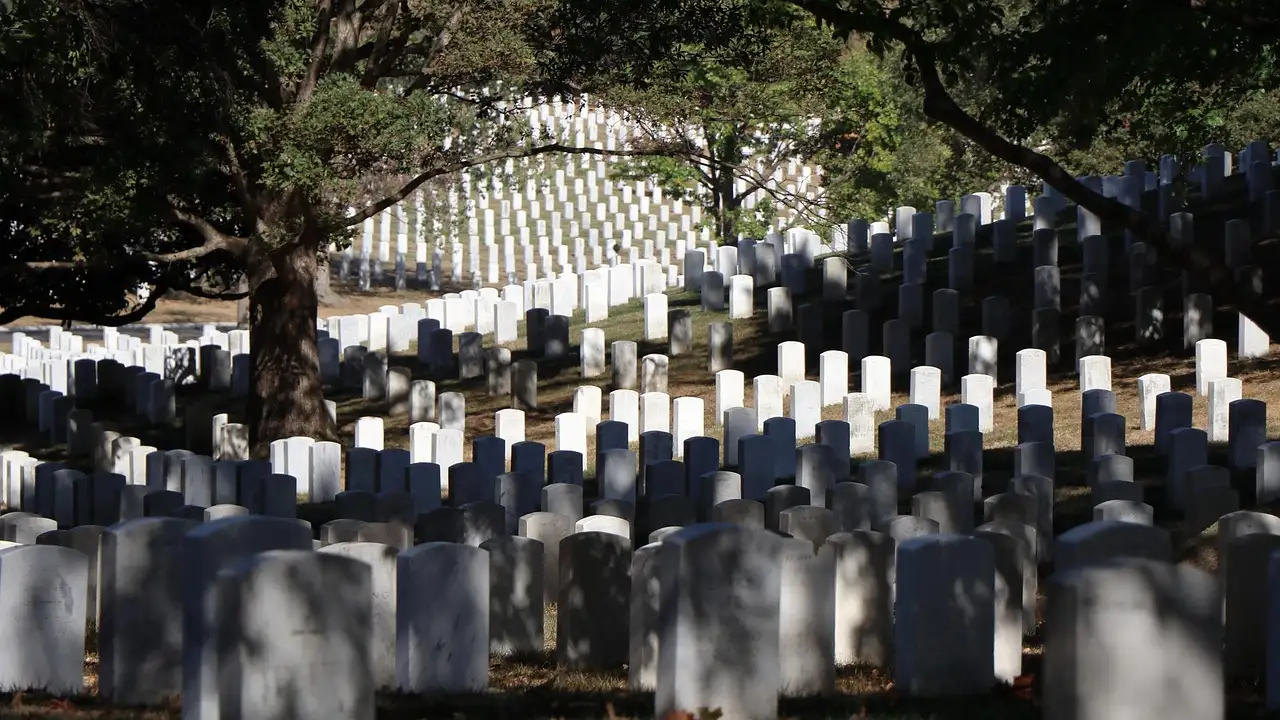 Rows of white headstones on a shaded slope at Arlington National Cemetery