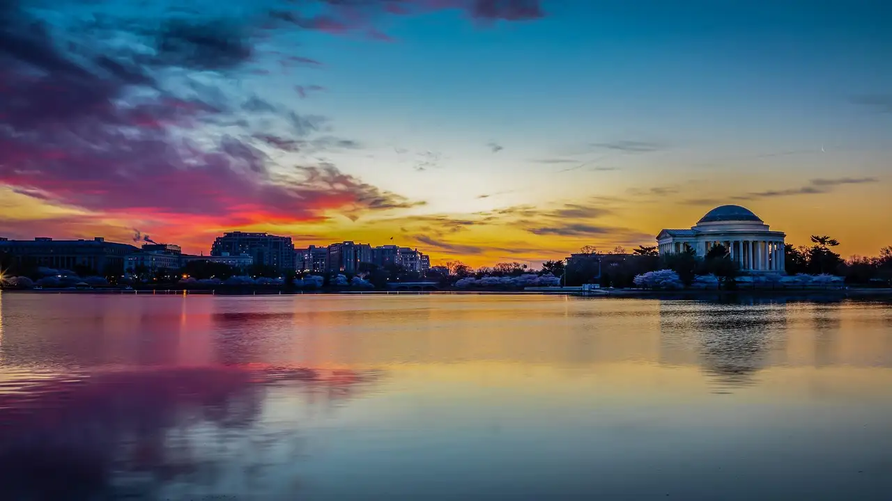 Jefferson Memorial across the calm Tidal Basin under a pink and orange sky