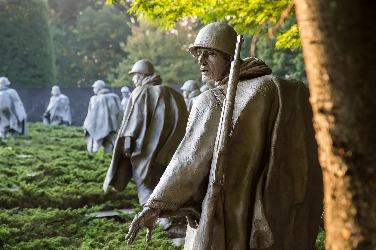 Steel soldier statues in ponchos walking through shrubs at the Korean War Veterans Memorial