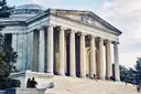 The Jefferson Memorial's columns and dome, with visitors sitting on its steps.
