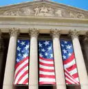Columns and pediment of the National Archives Building with flag banners hanging between them