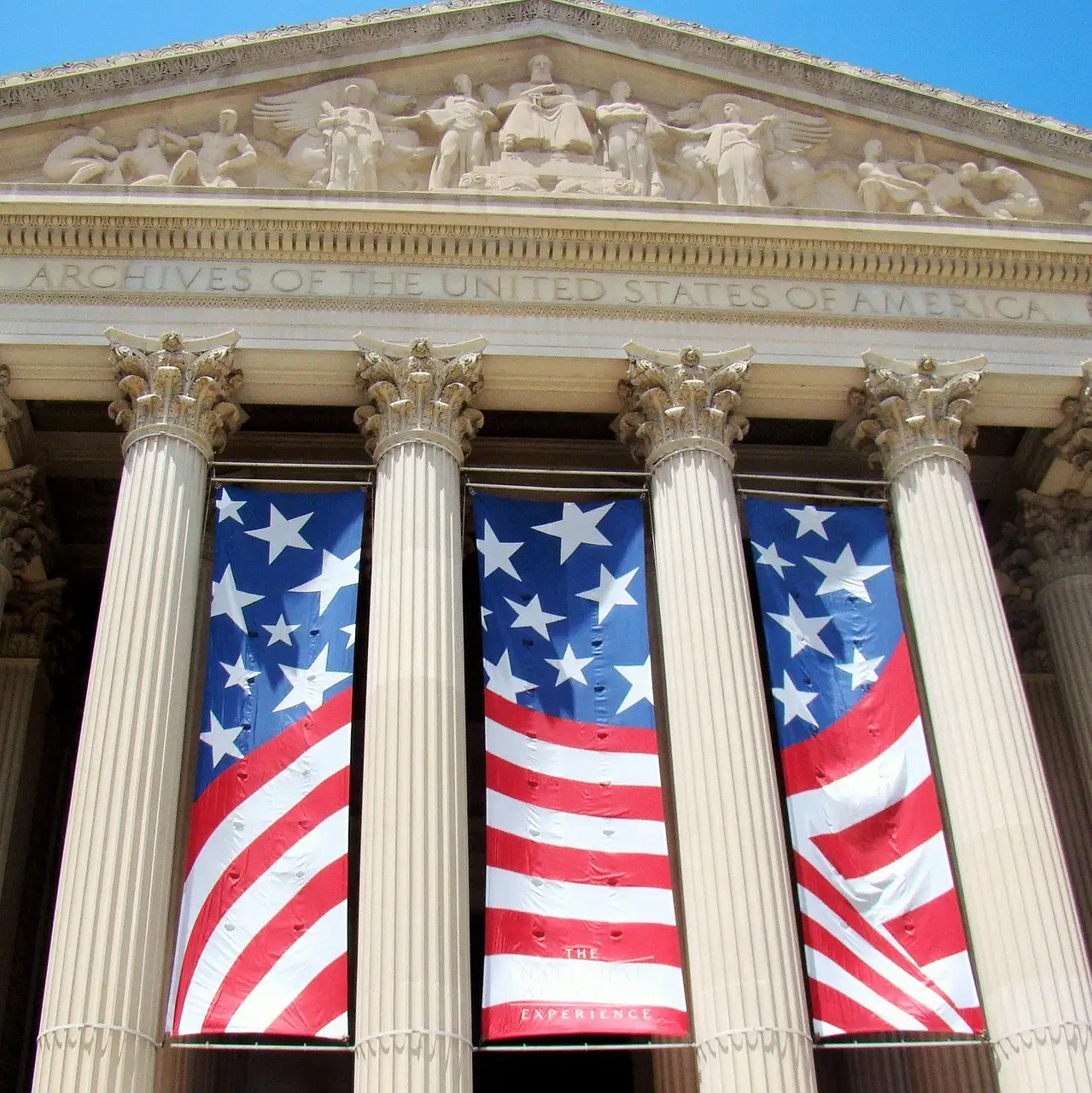 Columns and pediment of the National Archives Building with flag banners hanging between them