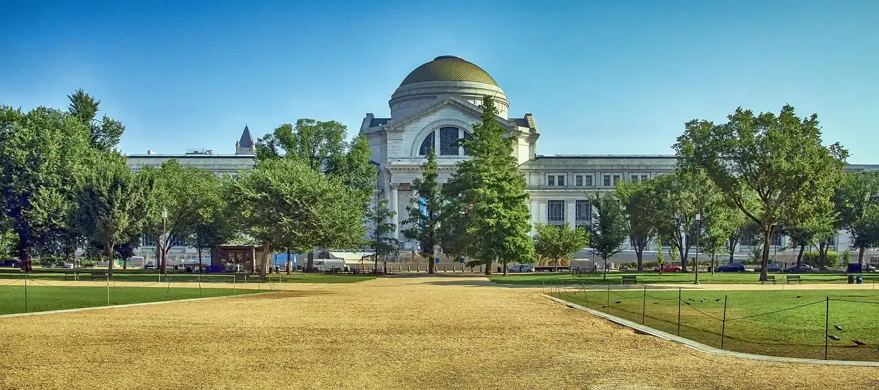 Domed National Museum of Natural History behind trees across the National Mall lawn