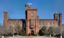 Red sandstone Smithsonian Castle with towers and flag under a blue sky on the National Mall
