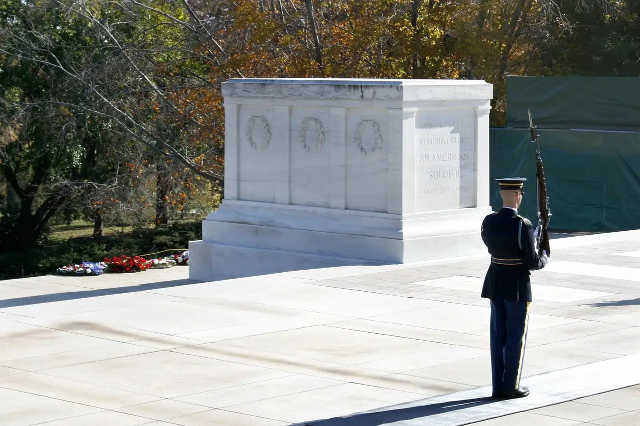 Sentinel with rifle guarding the white marble Tomb of the Unknown Soldier