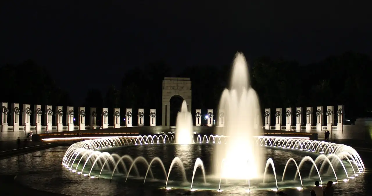 World War II Memorial at night with lit fountain, ring of pillars and the Pacific arch