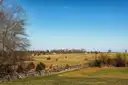 Open fields and a wooden rail fence on the Gettysburg battlefield under a blue sky