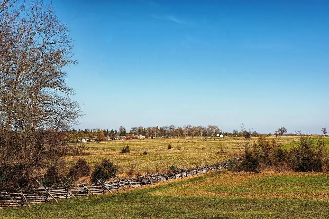 Open fields and a wooden rail fence on the Gettysburg battlefield under a blue sky