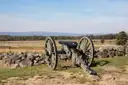 A Civil War cannon beside a stone wall on the Gettysburg battlefield