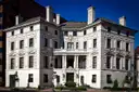 A large white Gilded Age mansion with tall chimneys on a Washington, DC street corner