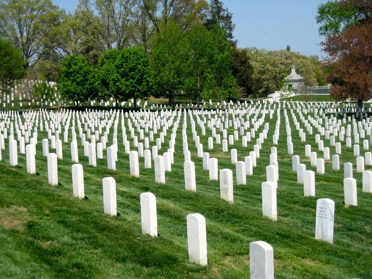 Rows of white headstones on a green slope at Arlington National Cemetery