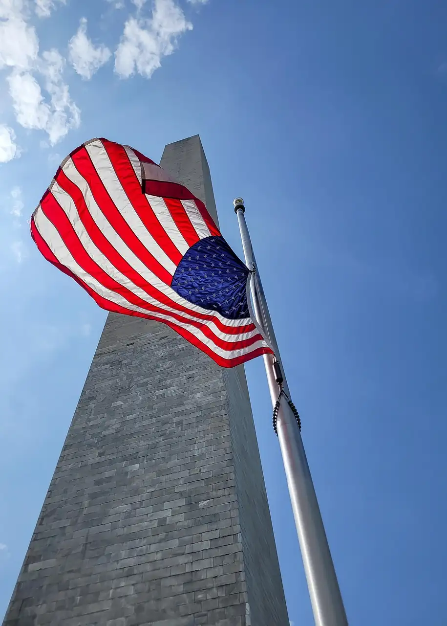 The Washington Monument seen from its base, with a US flag in front