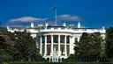 The north side of the White House behind its lawn and fountain, with trees on both sides