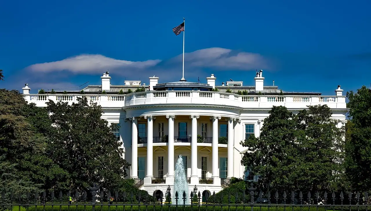 The north side of the White House behind its lawn and fountain, with trees on both sides