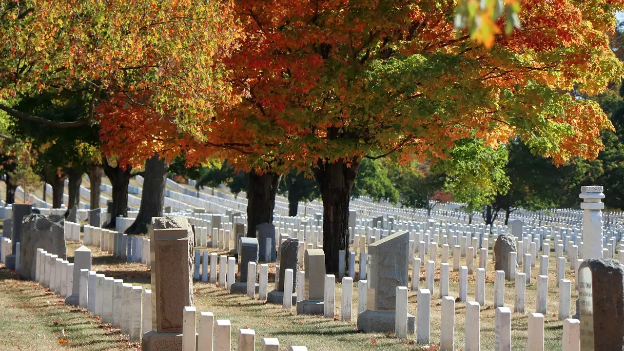 White headstones under orange autumn trees at Arlington National Cemetery