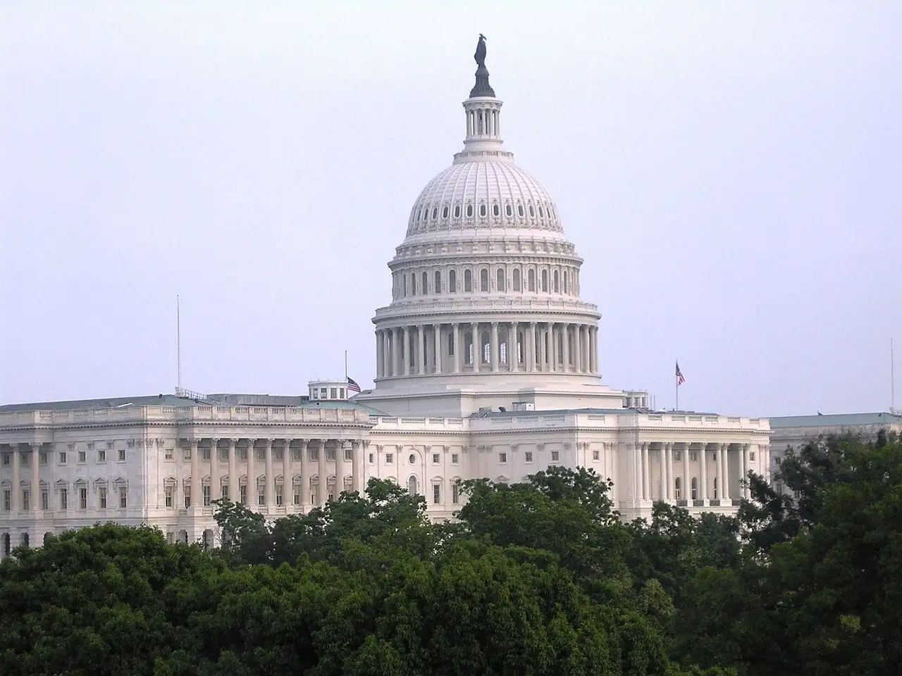 The US Capitol dome rising above green trees