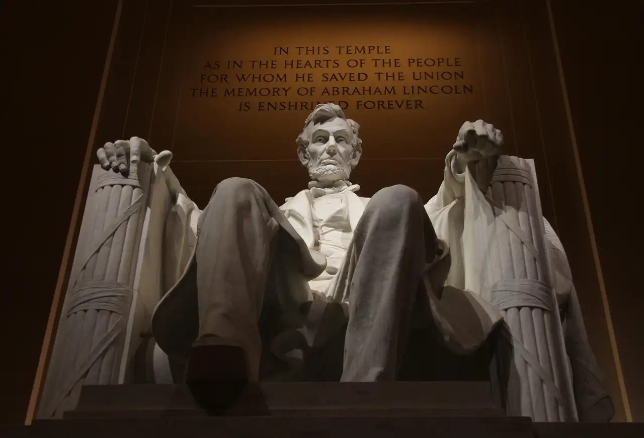 The lit statue of Abraham Lincoln inside the Lincoln Memorial, seen from below