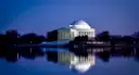 The Jefferson Memorial at dusk, its dome lit and reflected in the still water of the Tidal Basin