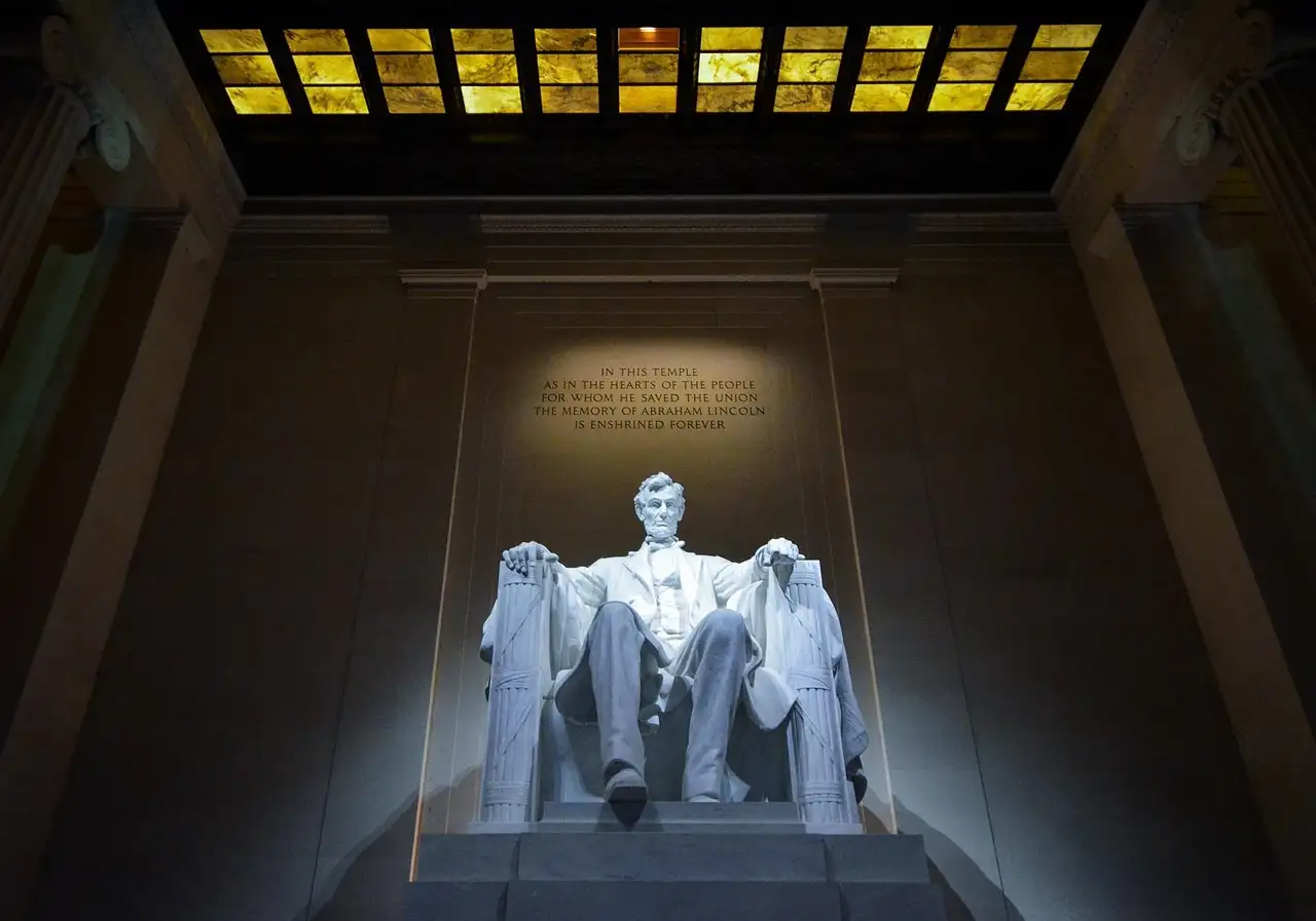 The seated statue of Abraham Lincoln lit inside the Lincoln Memorial