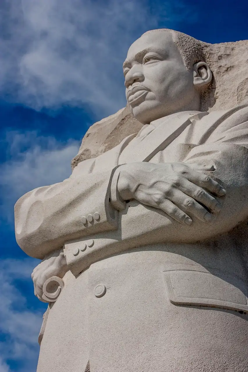 The granite statue of Martin Luther King Jr. at his memorial, arms folded, against a blue sky