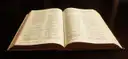 An open antique Bible lying on a dark surface.