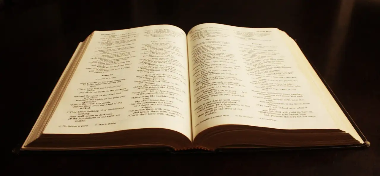 An open antique Bible lying on a dark surface.