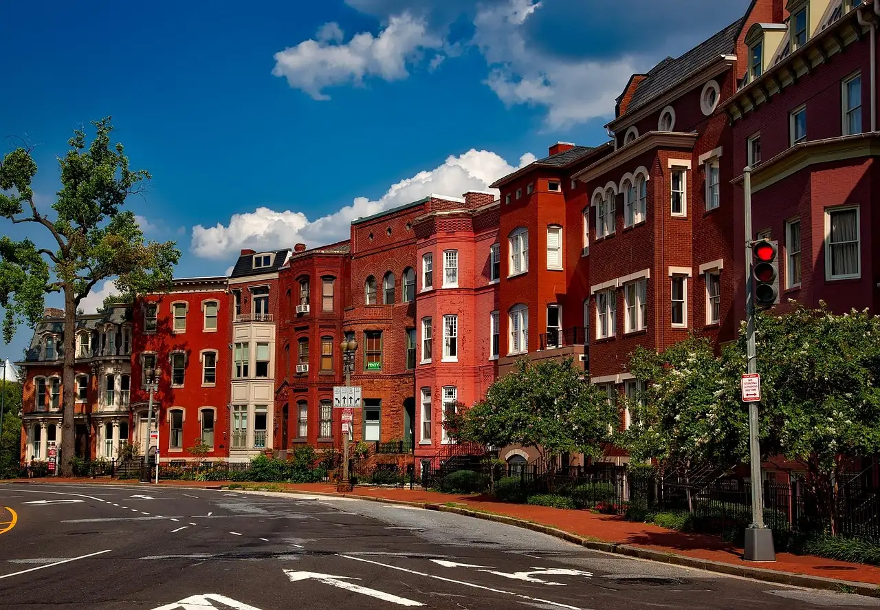A row of red brick town houses on a street corner under a blue sky