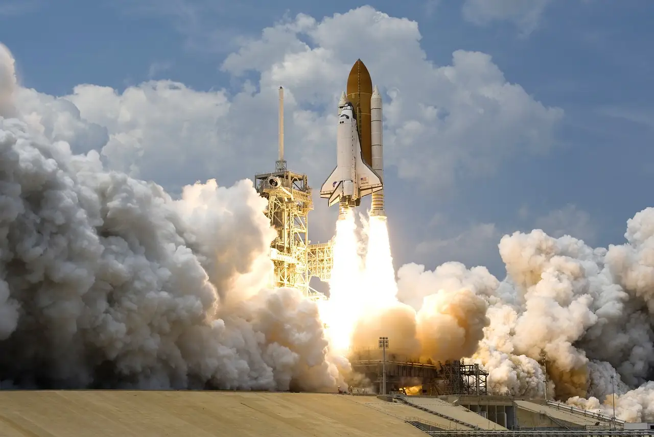 A Space Shuttle lifting off from its launch pad in a cloud of smoke and steam.