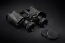 A pair of old black binoculars with their lens caps beside them on a dark surface.
