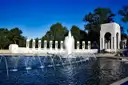 Fountains and an arch of the World War II Memorial under a blue sky