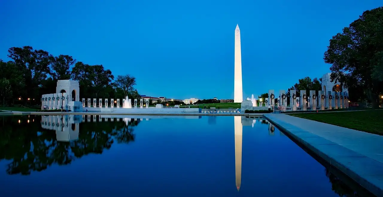 The World War II Memorial and the Washington Monument reflected in still water at dusk