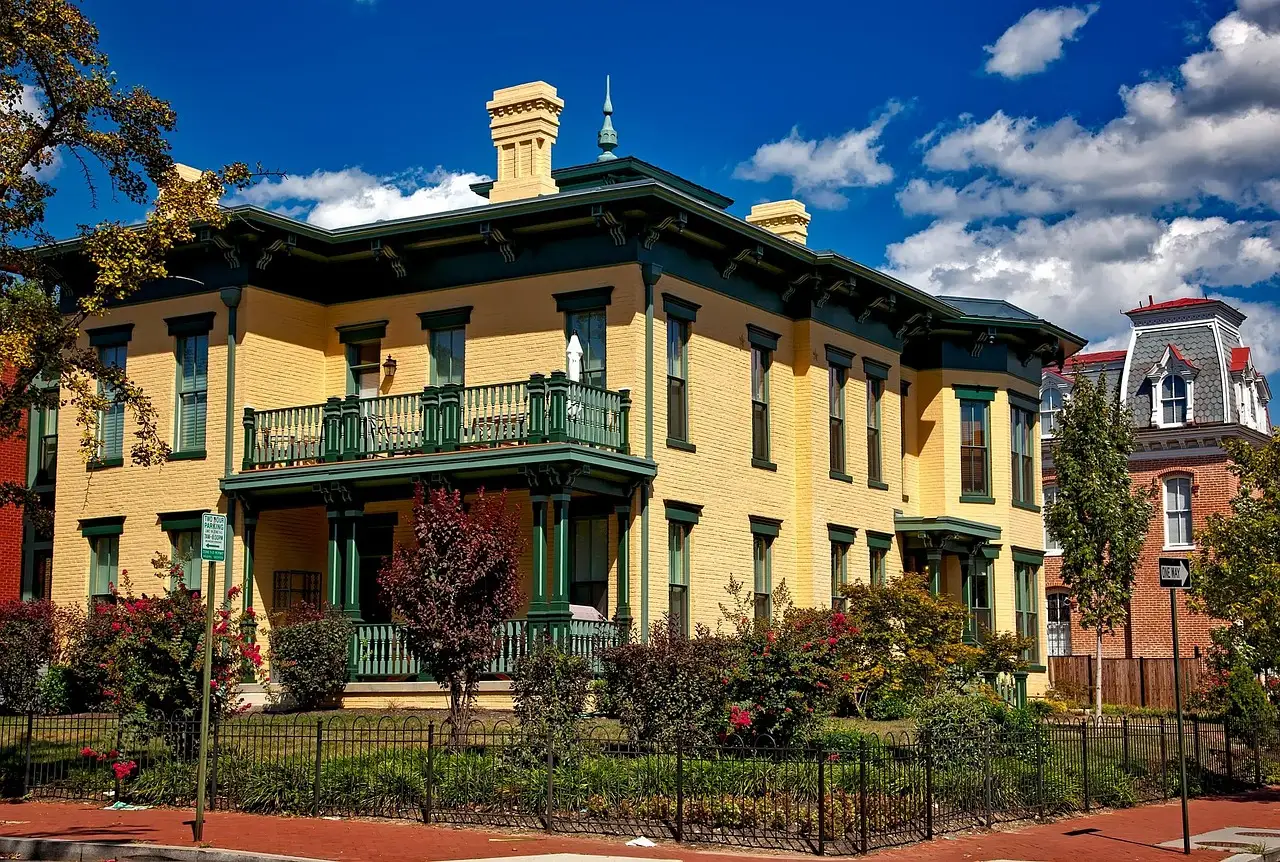 A yellow Victorian house with a green-railed porch on a street in LeDroit Park, Washington, DC.