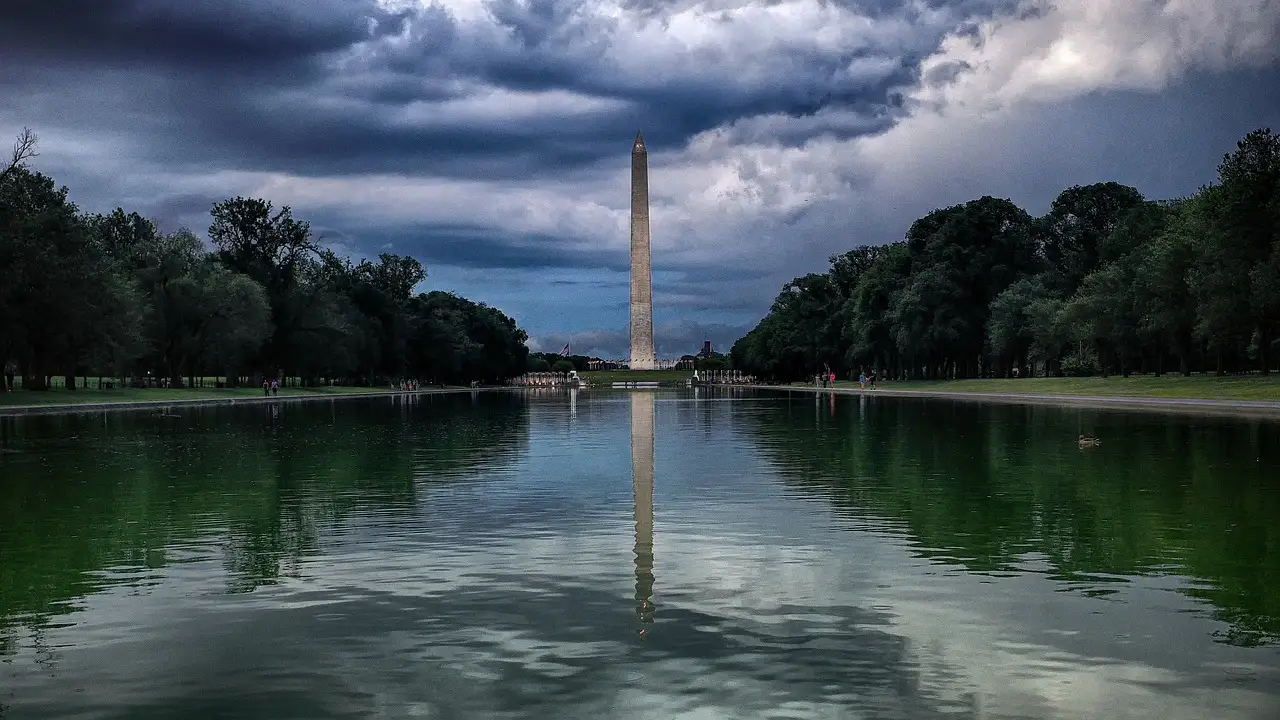 The Washington Monument across the Reflecting Pool under heavy storm clouds.