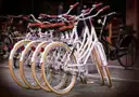 A row of white bicycles with brown tires parked on a street