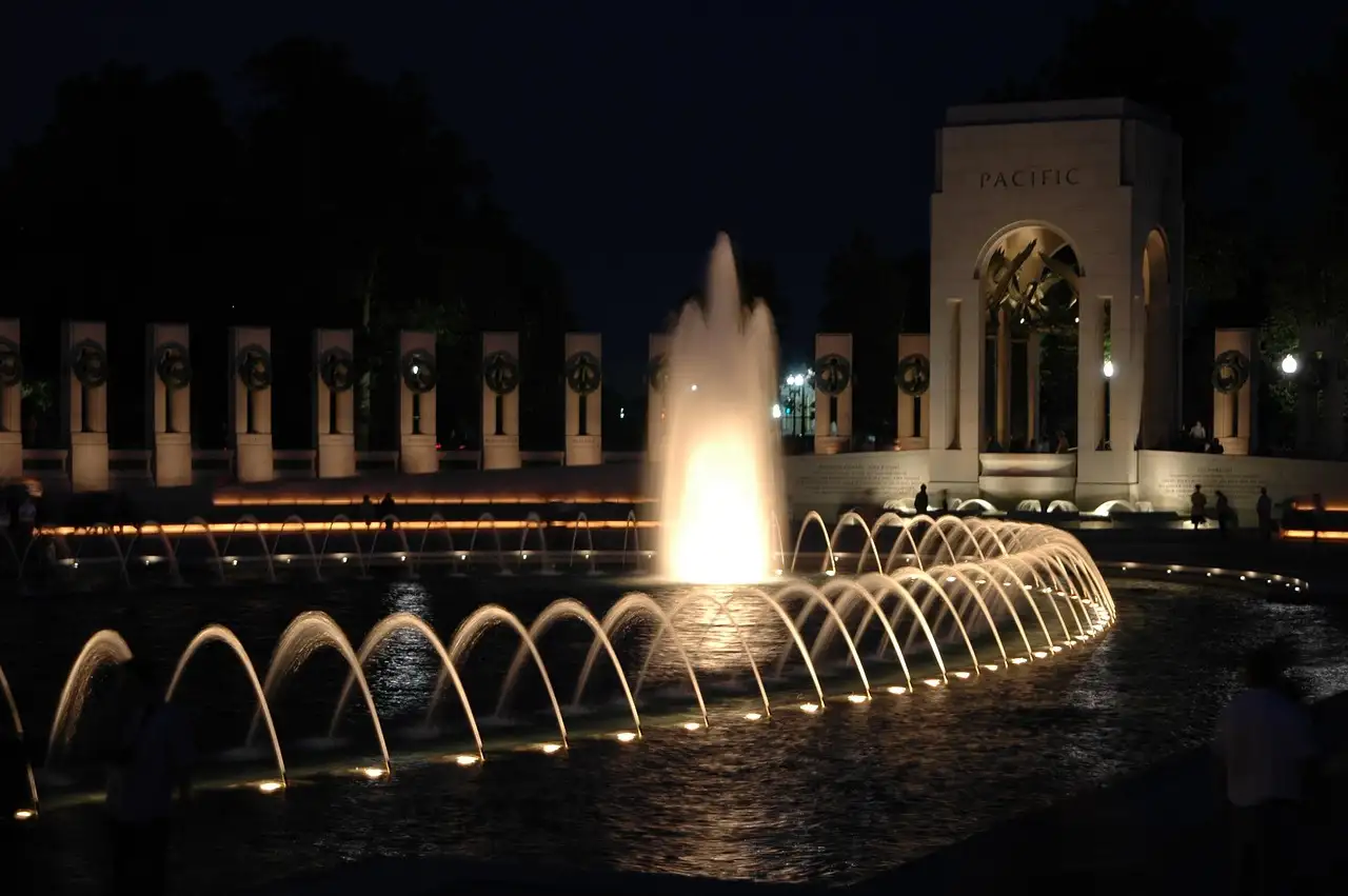The World War II Memorial at night, its fountain and stone pillars lit up around the pool