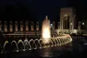 The World War II Memorial at night, its fountain and stone pillars lit up around the pool